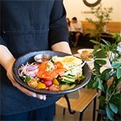 Person holding a black plate fresh salad