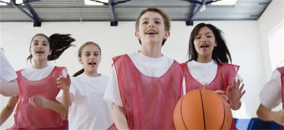 Kids playing basketball in a gym.