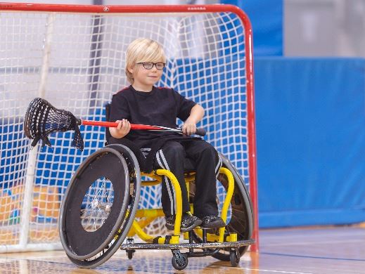 Young boy in a wheelchair playing lacrosse as the goalie