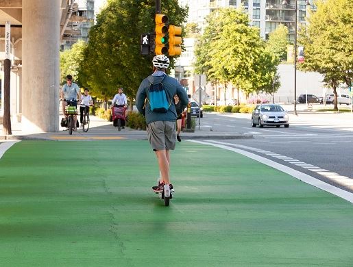 Escooter rider in crosswalk wearing a helmet