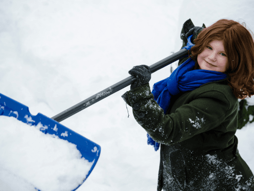 Child holding a blue shovel with snow