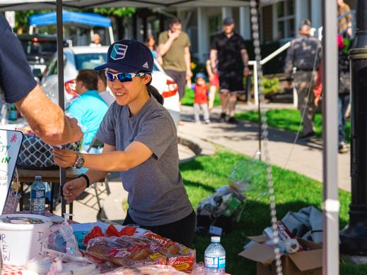 Woman providing a prize at a tent set up at a Coquitlam block party.