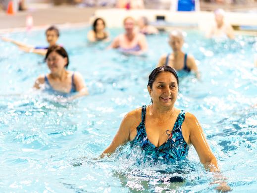 Image of an adult woman standing and smiling in the shallow end of a pool