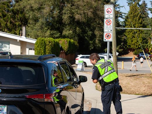 Bylaw enforcement office chatting with driver of vehicle in a school loading zone 