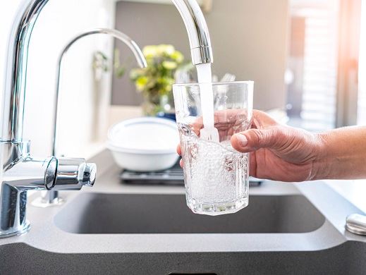 Clean drinking water coming from tap into glass