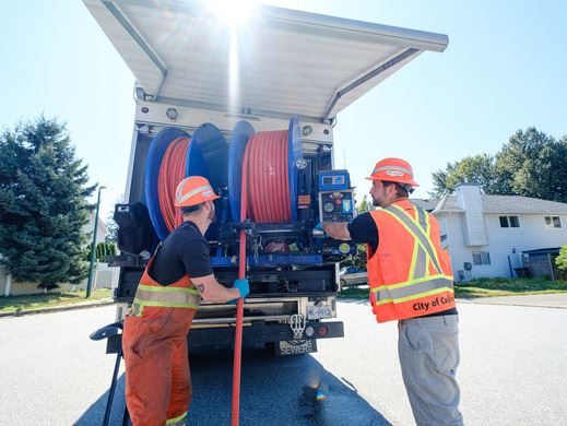 Public works staff unspooling a cable/hose 