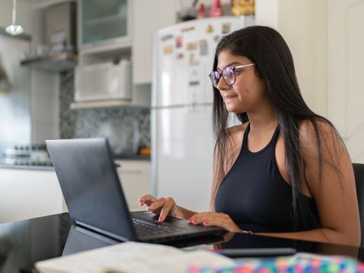 A young woman sits at a desk with a laptop computer open in front of her