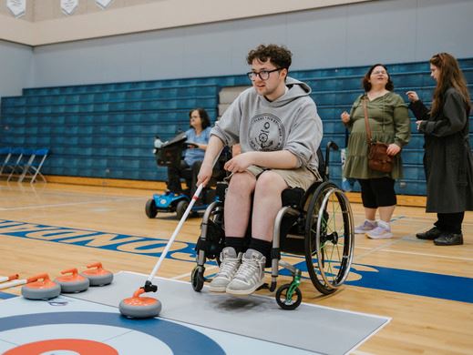 Individual in wheelchair curling in gymnasium