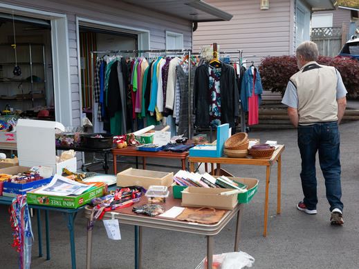 a man walks through a neighbour's garage sale for the City-Wide Garage Sale and Giveaway Event