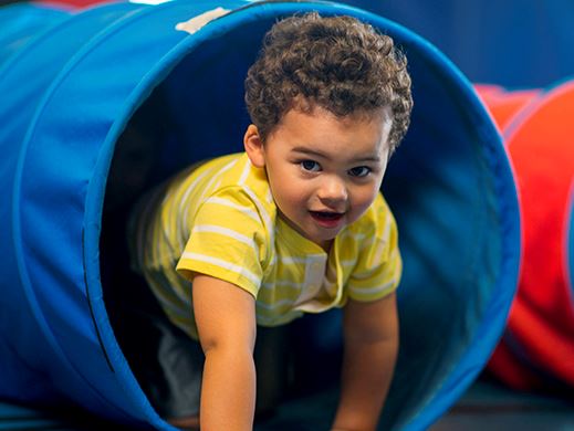 A young child crawls out of a tunnel