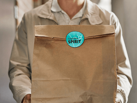 Mad holding brown paper delivery bag with food.