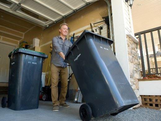 Adult Rolling Garbage Cart out to Curb