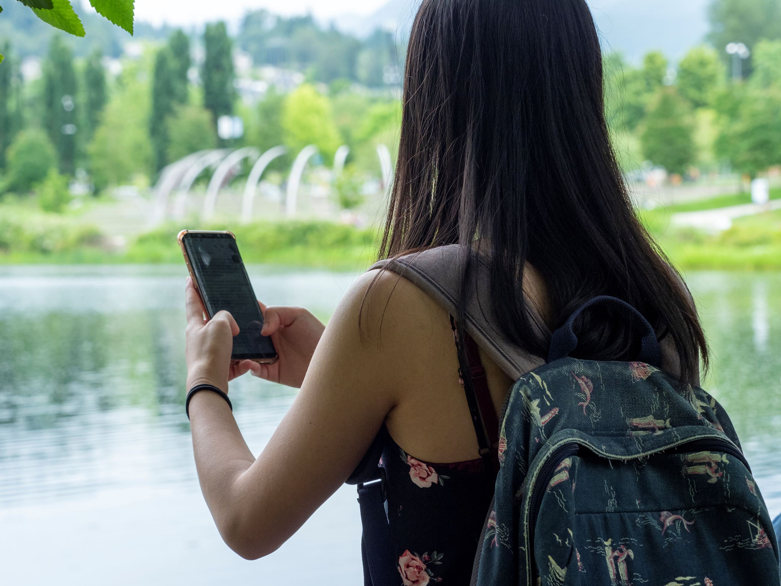 A woman holds up her cell phone in front of Town Centre Park