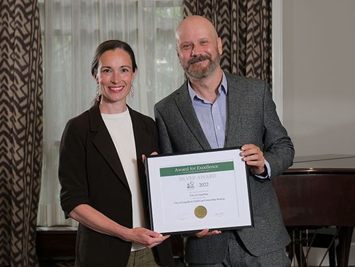 A woman and a man hold up a framed award