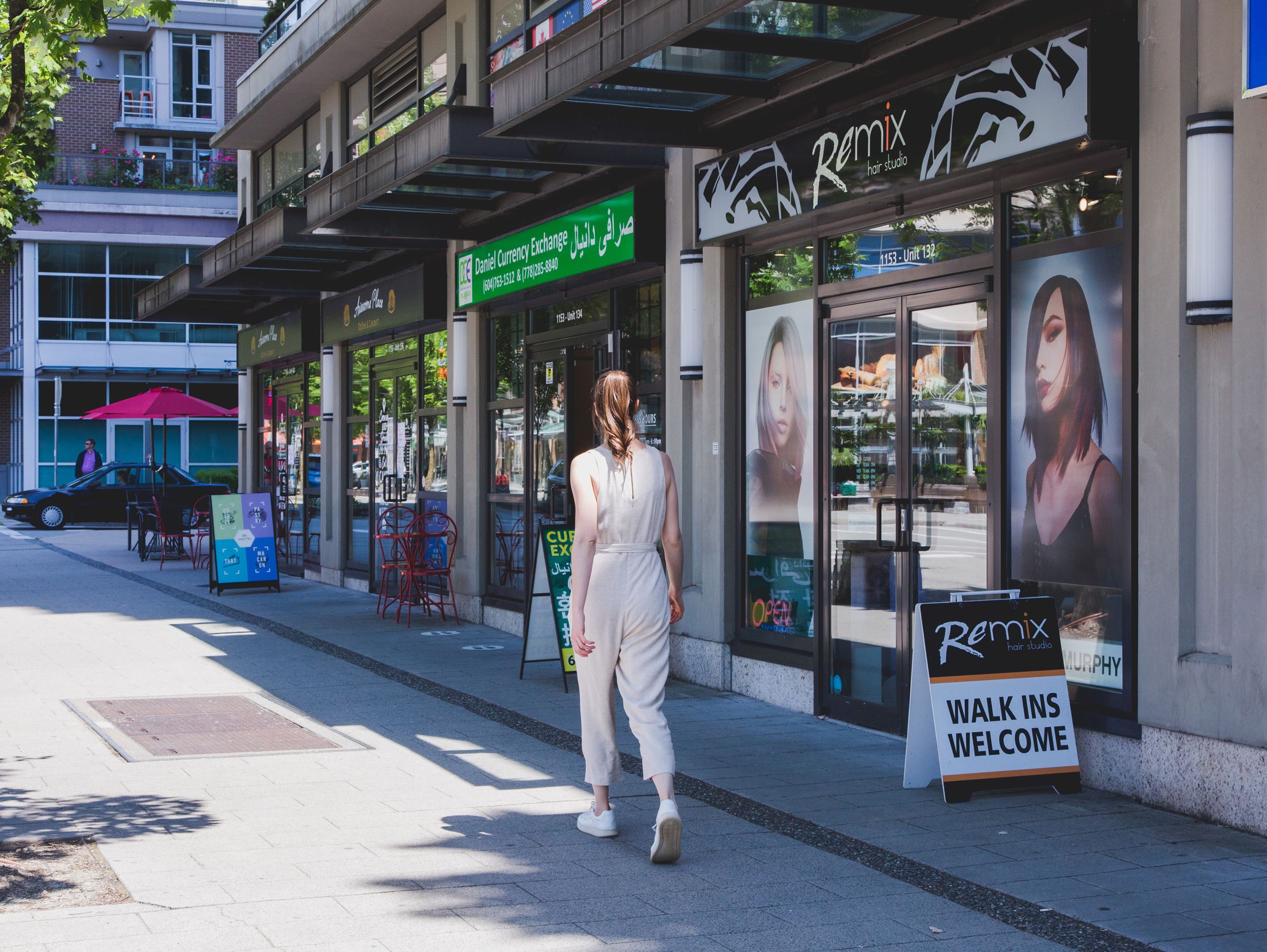 A young woman walks on the sidewalk in City Centre in front of a number of local businesses