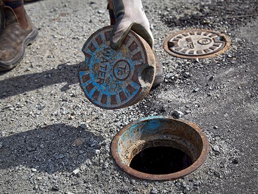 A City of Coquitlam Public Works employee replaces the lid on a sewer cover