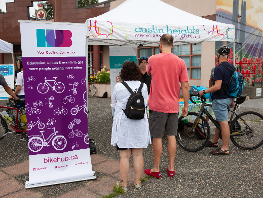A group of people stand at a HUB Cycling display tent