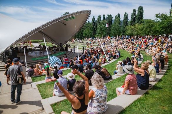 Crowd enjoying an outdoor concert in an amphitheatre on a sunny day