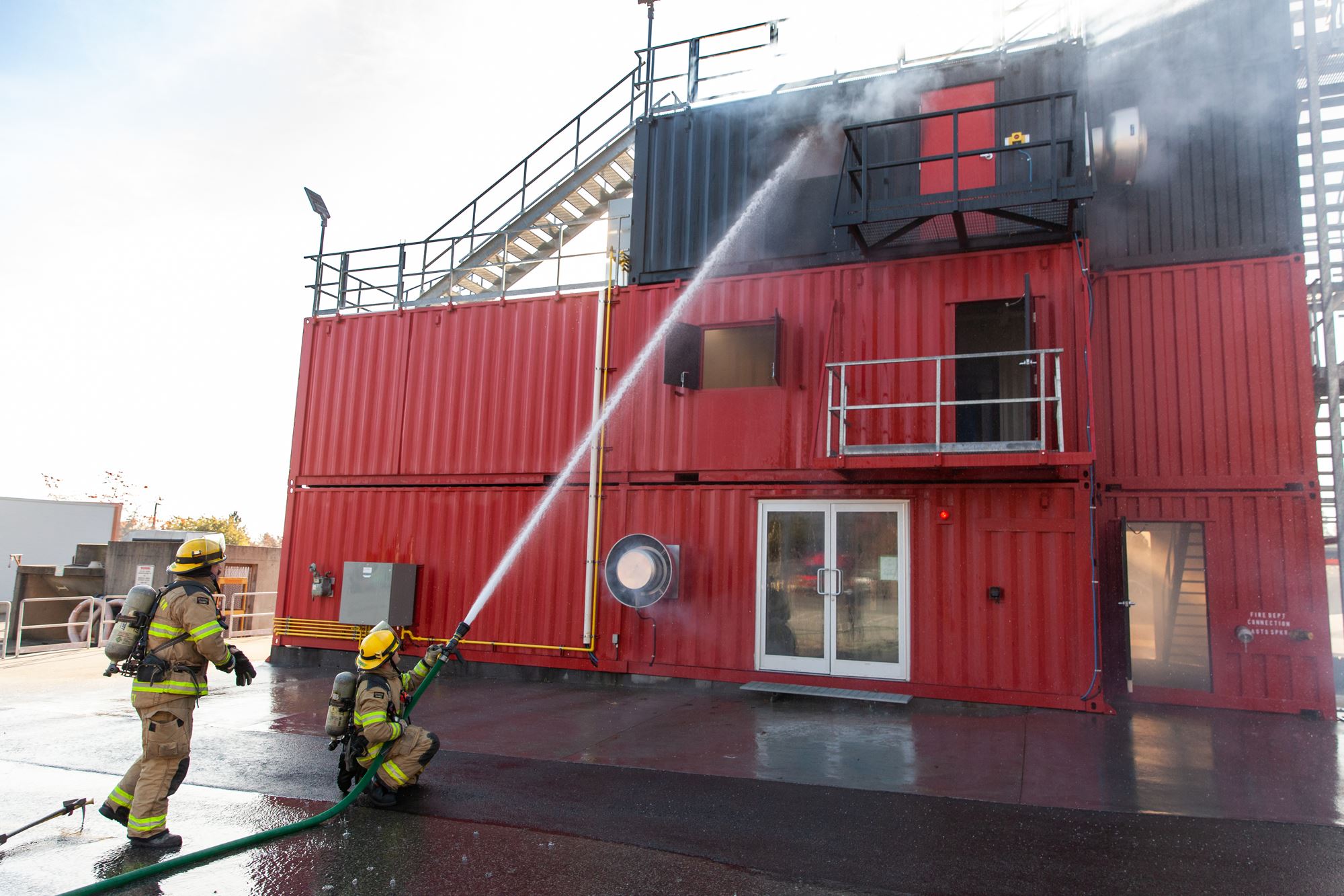Fire fighters using water hoses to extinguish fire in training exercise