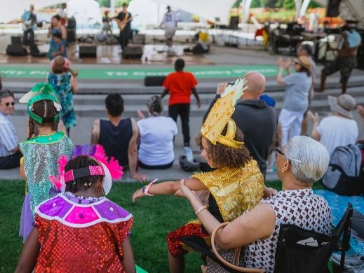 Crowd with children in bright costumes watching a musical performance